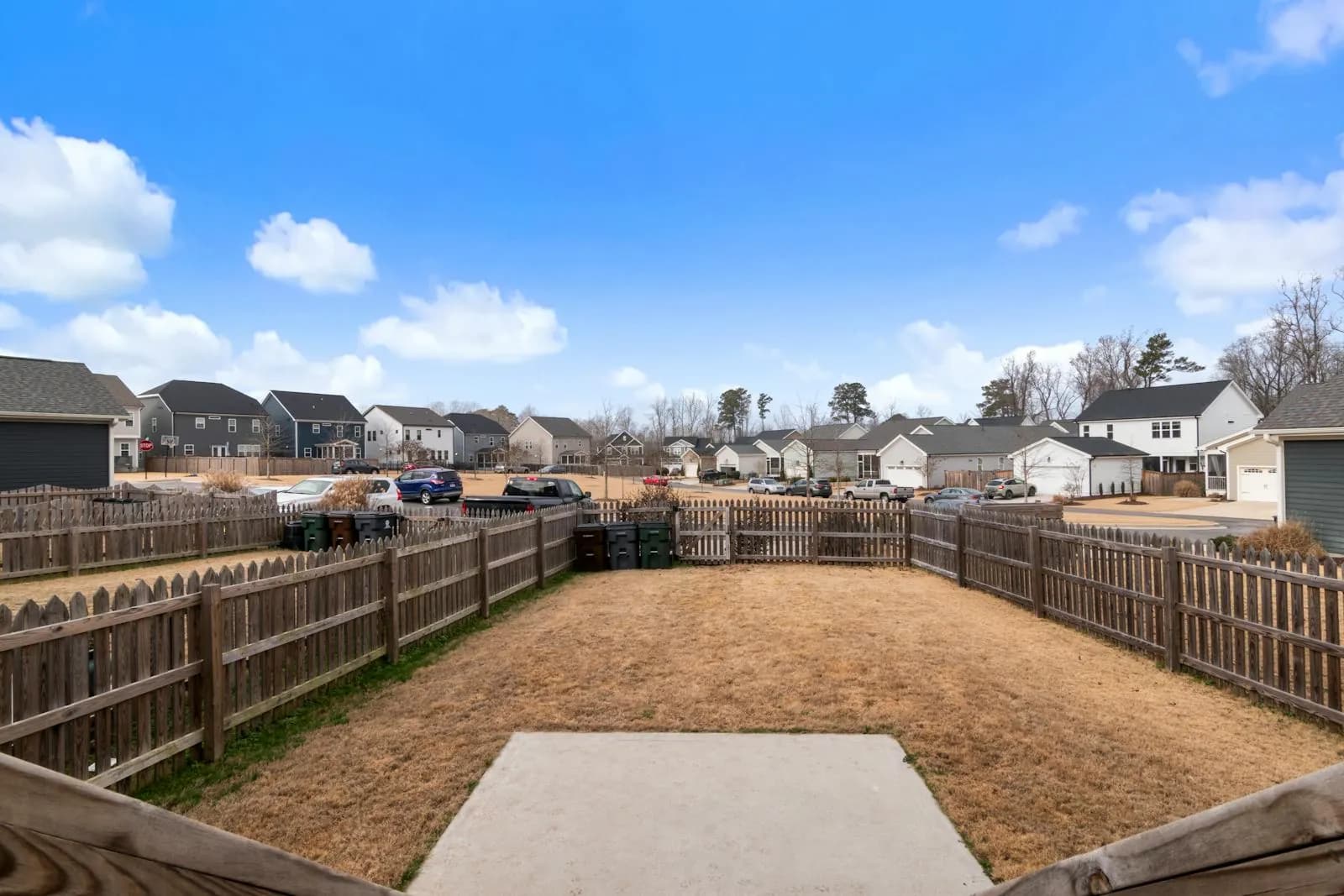 Sunny suburban backyard with wood fencing and neighboring homes.