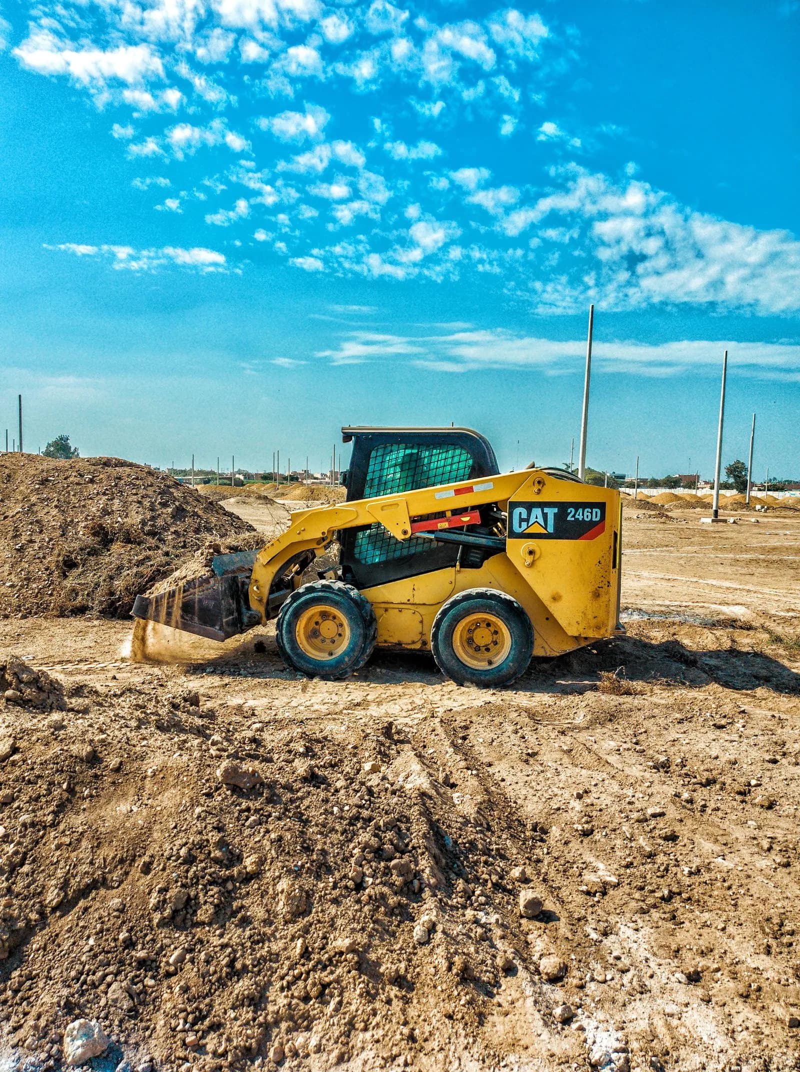 Skid-steer loader working on a sunny construction site.
