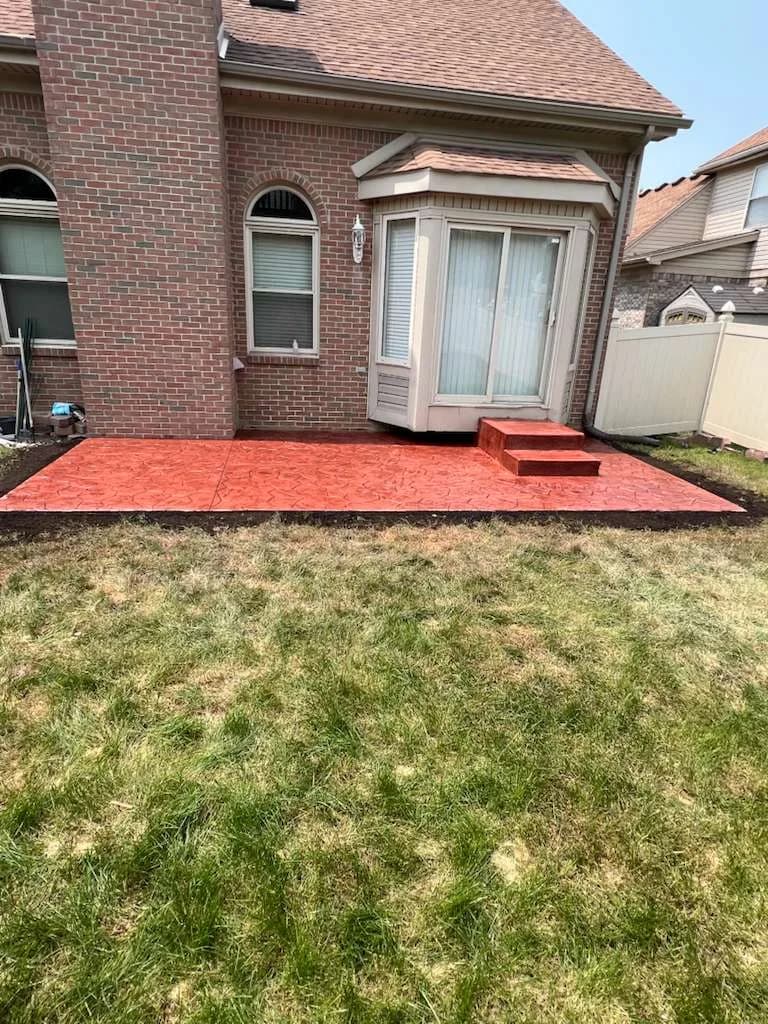 Finished stamped concrete backyard patio with step at a residential home