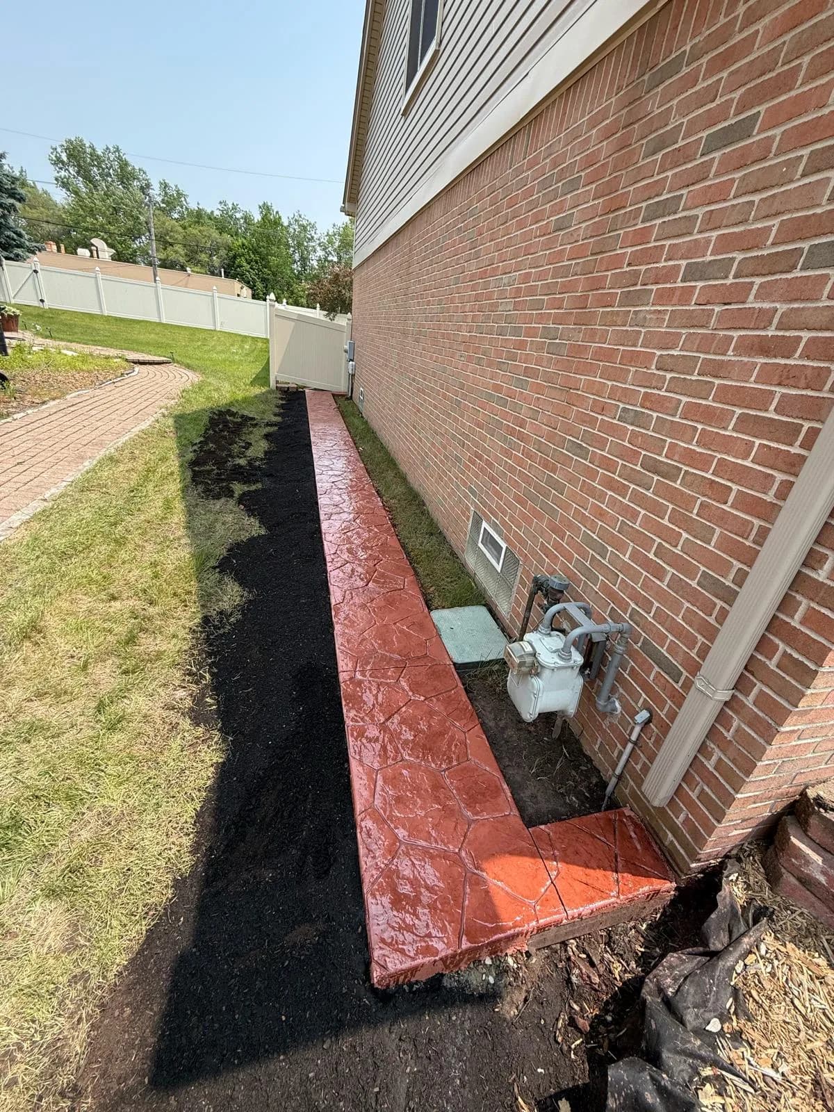 Stamped concrete walkway running along the side of a brick home