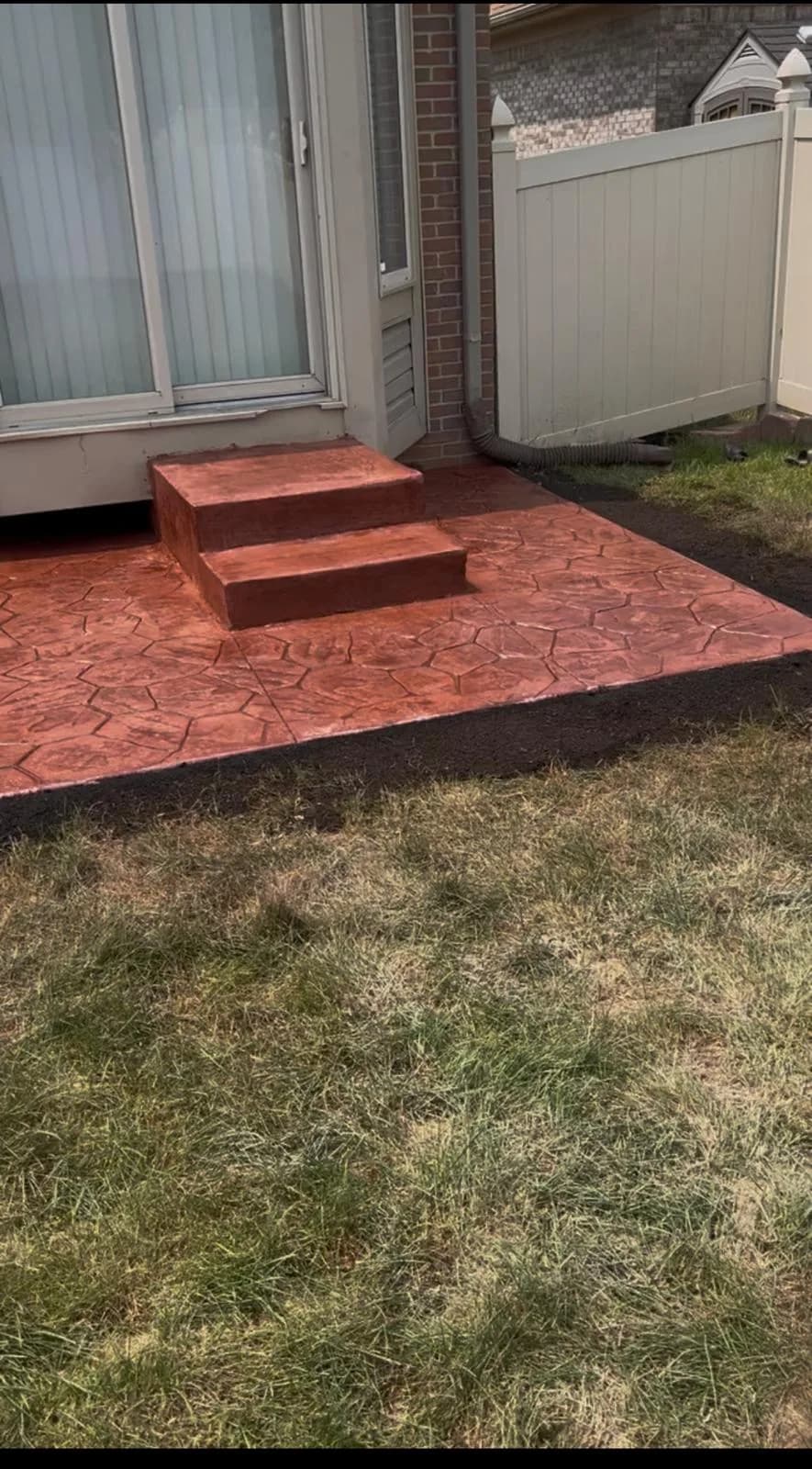 Stamped concrete patio with finished steps leading to a home entrance
