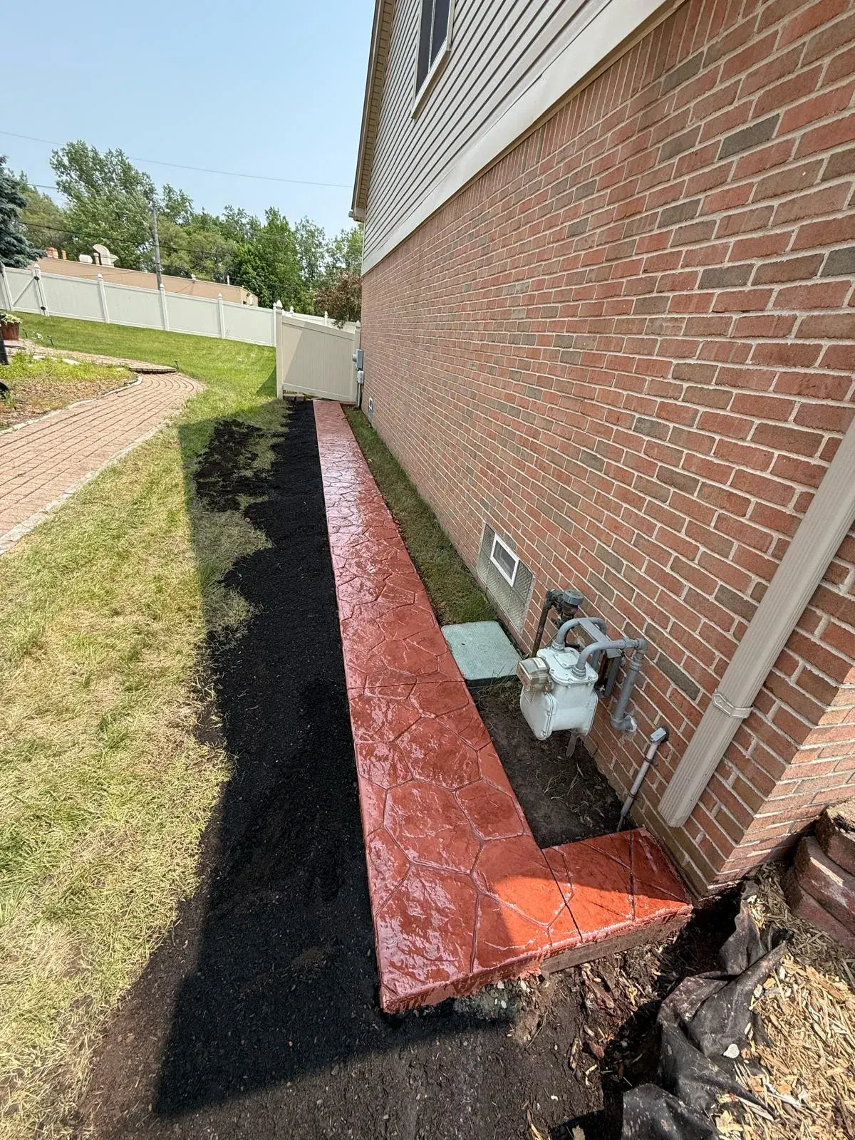 Stamped concrete walkway running along the side of a brick home